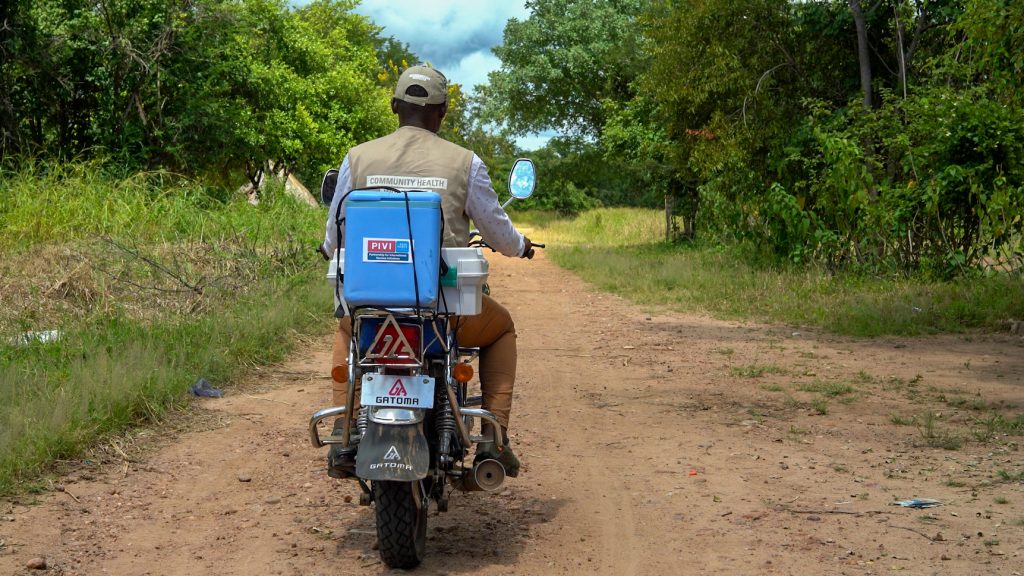 Community health worker delivering vaccines by motorbike with PIVI cold chain equipment in a rural setting