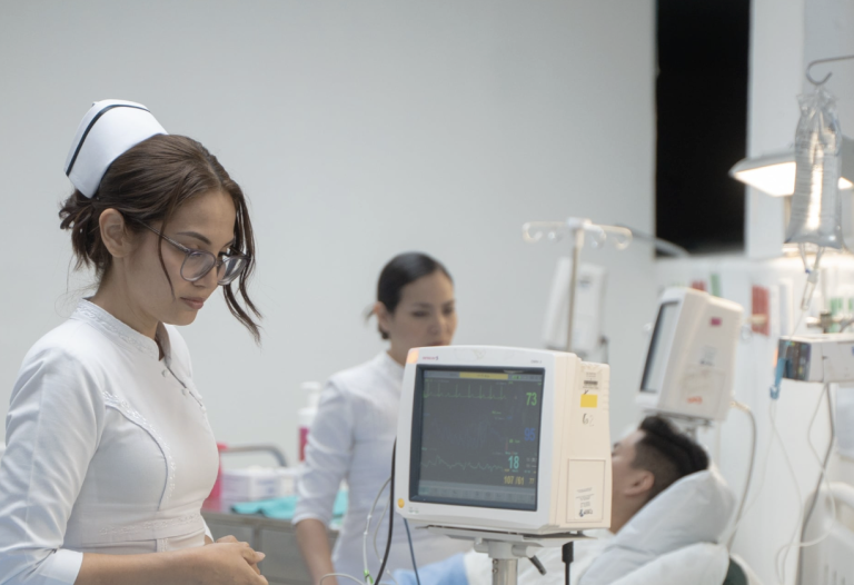Nurse monitoring a patient and reviewing vital signs in a hospital setting